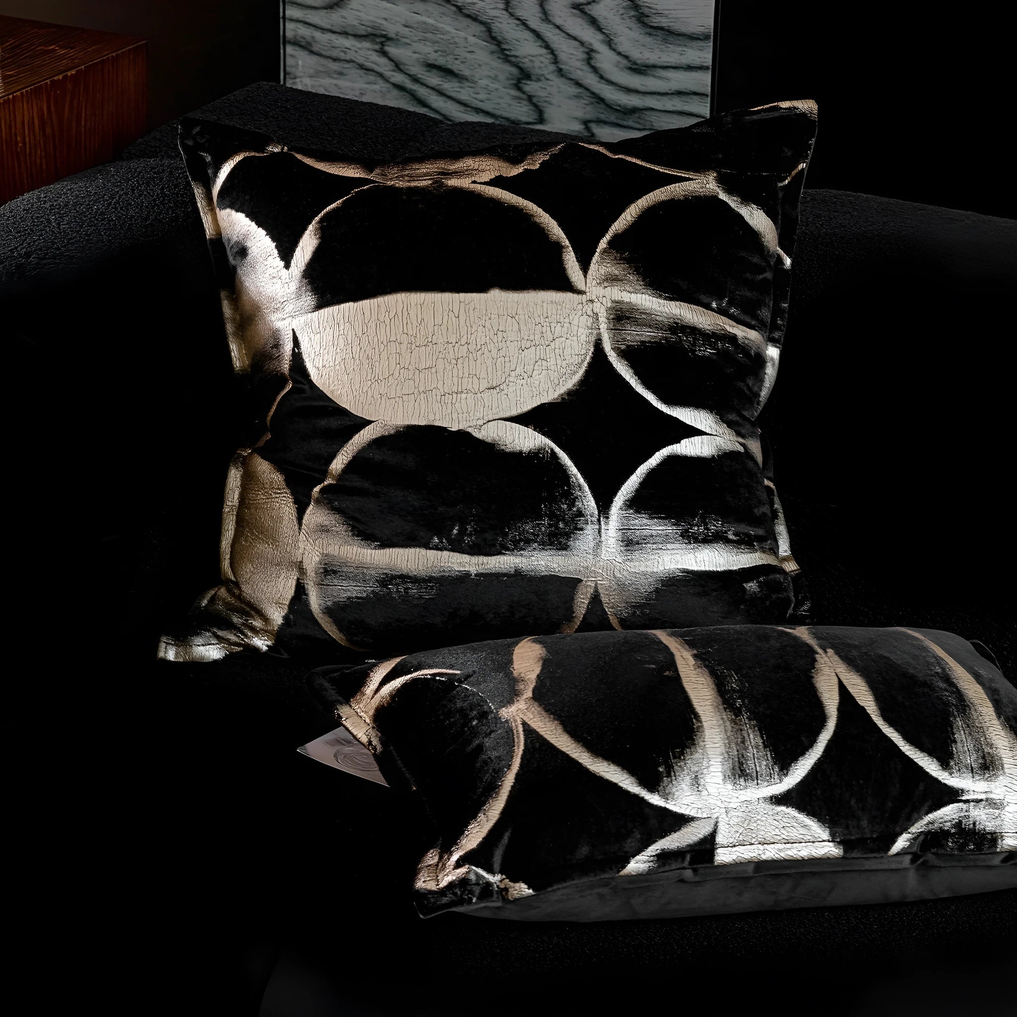 Black and gold abstract print flannel decorative cushion pillow on a sofa.