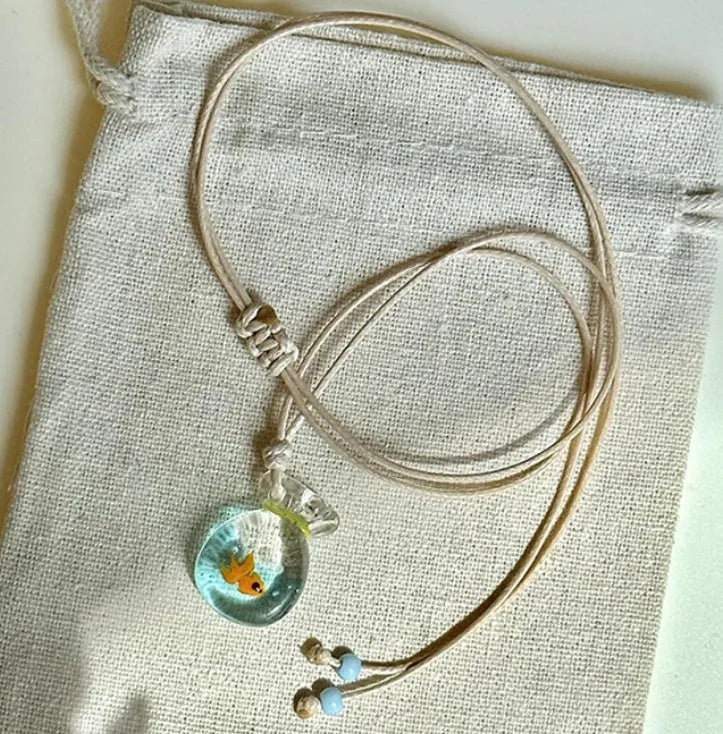 Women's necklace with coloured glaze joker pendant on a beige cotton and linen clavicle chain.