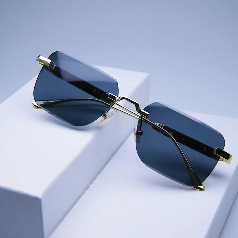 Frameless edge-cut sunglasses with gold frame, wood grain legs, and gradient grey lenses on a neutral background