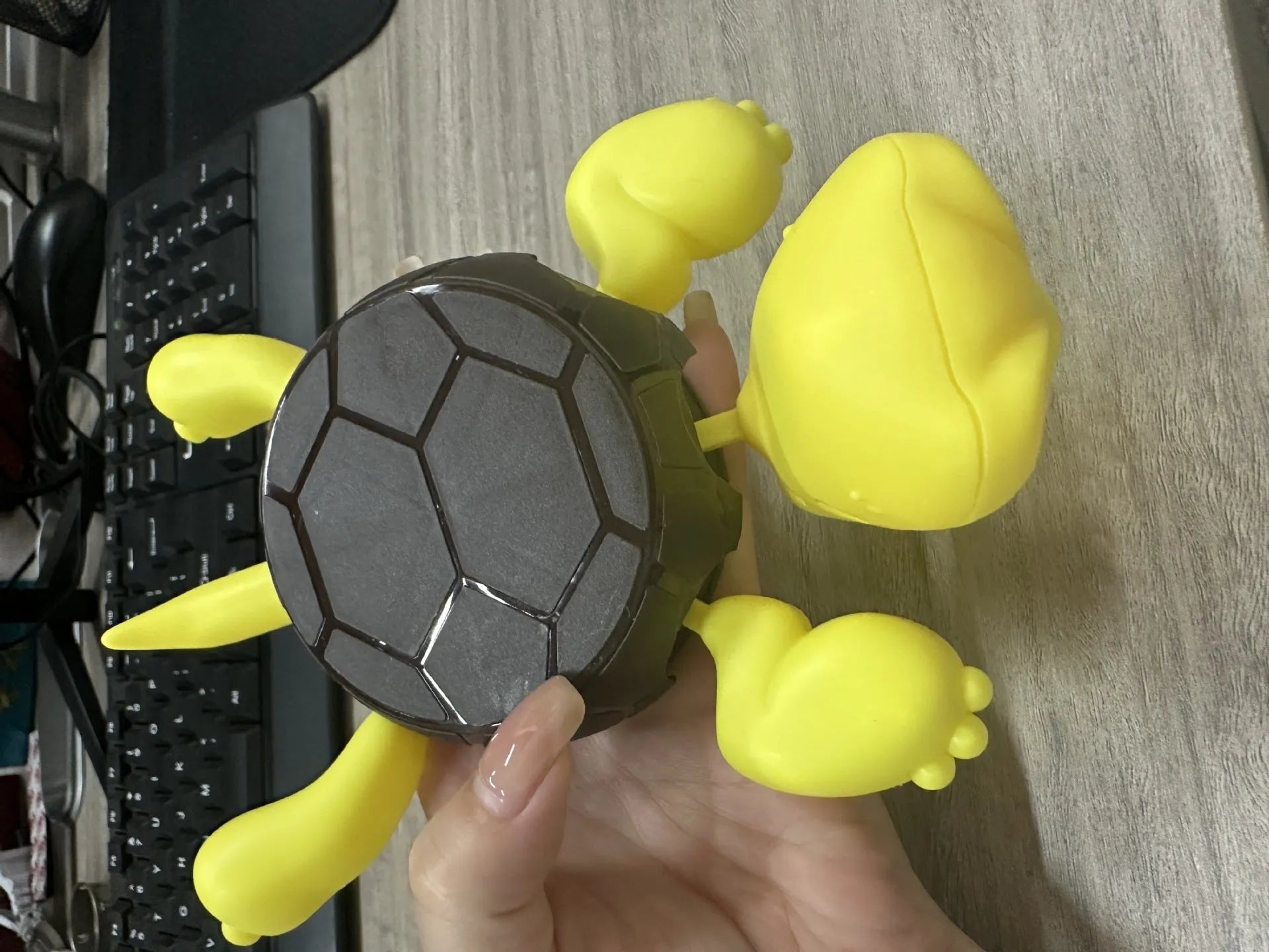 Turtle-shaped drink coaster made from ABS plastic in a light green colour on a wooden table.