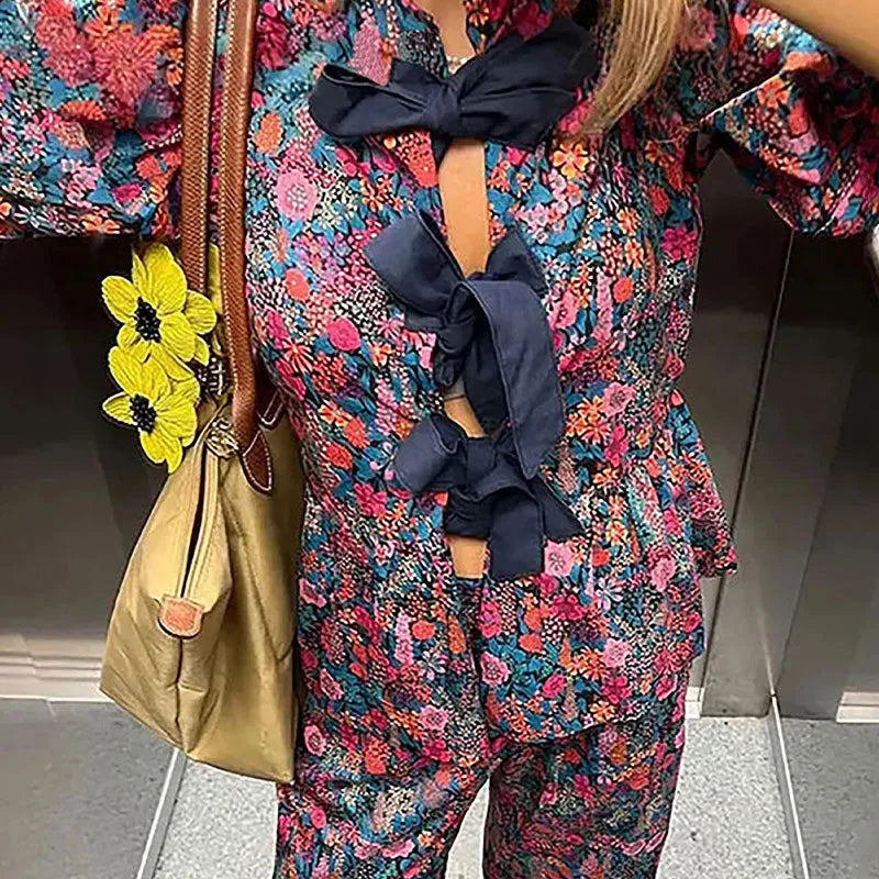 Women's floral print tie-neck blouse and trousers suit with puff sleeves.