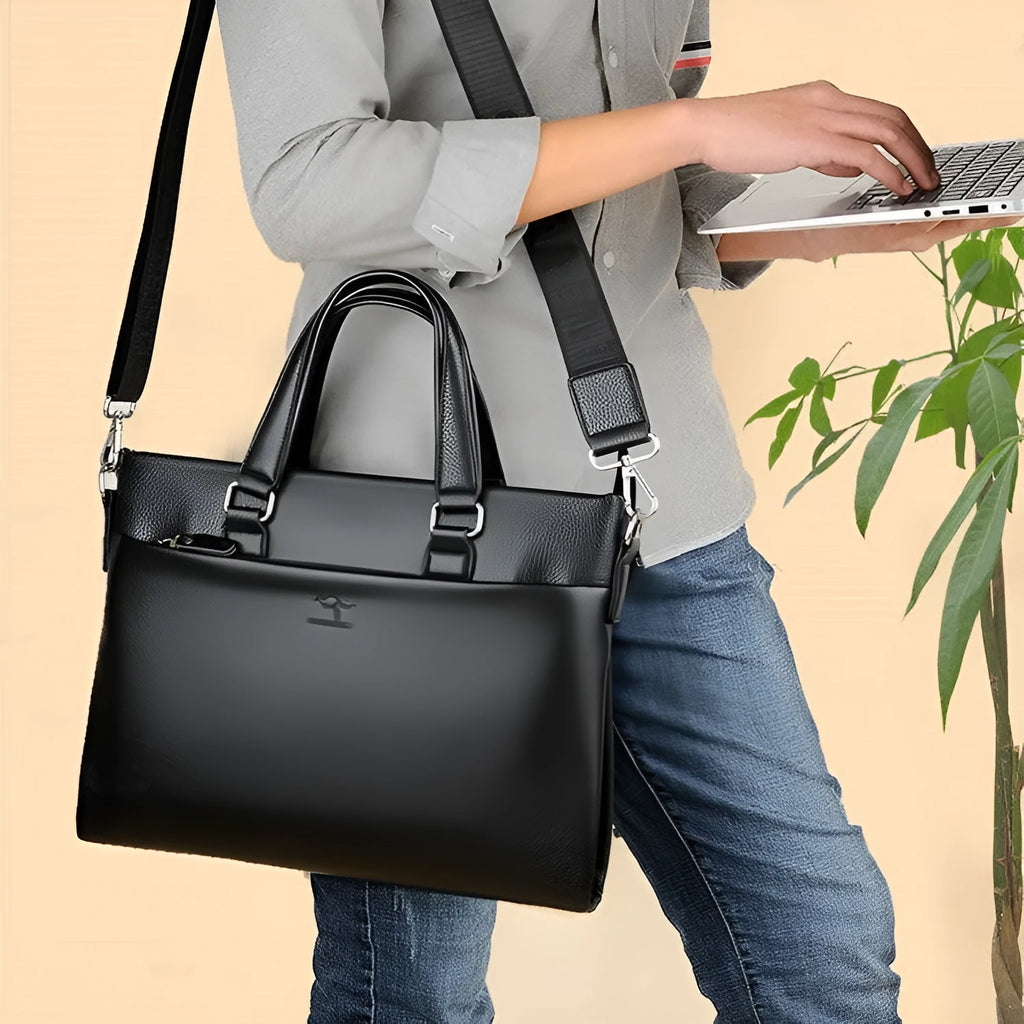 Black PU leather men's shoulder messenger bag with splicing style, shown next to a laptop