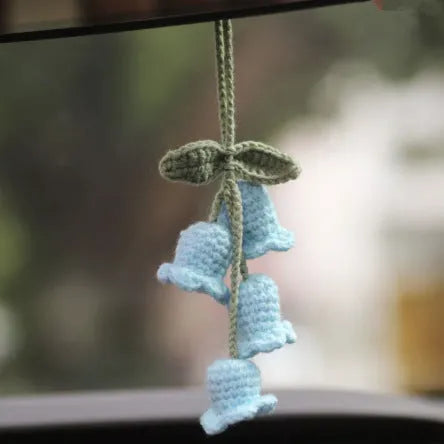 Green and white knitted wool car plant decoration hanging from a rope.