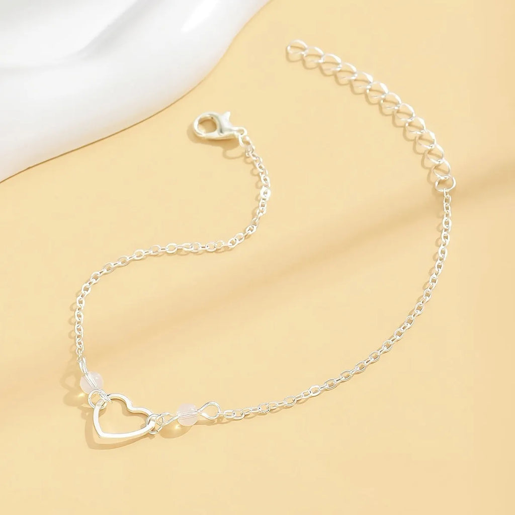 Adjustable gold or silver alloy anklet with a simple heart-shaped pendant.