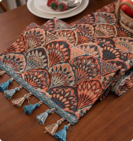 Long decorative table runner with handwoven tassels in a blue ginkgo leaf pattern on a wooden table.