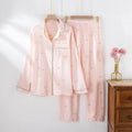 Women's pink cotton crepe pajama suit with long sleeves and trousers laid flat.