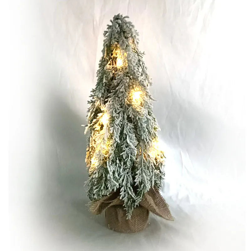 Small 24-inch artificial Christmas tree with snow sprayer finish and integrated lights on desktop