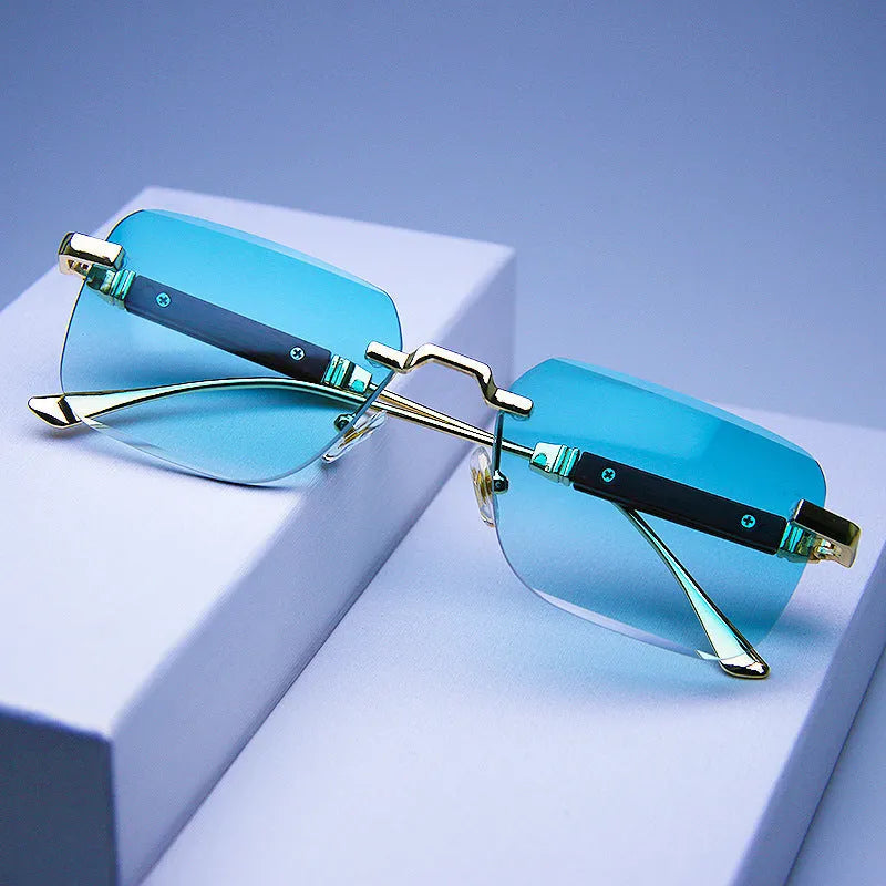 Frameless edge-cut sunglasses with gold frame, wood grain legs, and gradient grey lenses on a neutral background