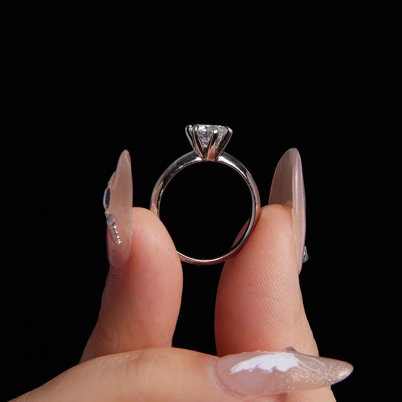Simple classic 6 claw 1 karat moissanite ring in silver on white background, US size 7