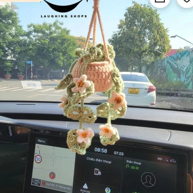 Green and white knitted wool car plant decoration hanging from a rope.