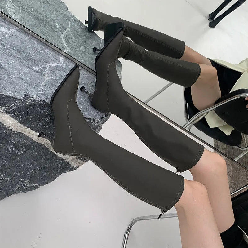 Black women's pointed toe below-knee boots with stiletto heel and back zipper on a white background.