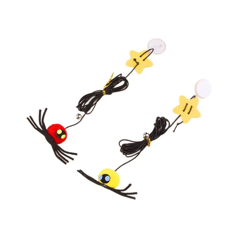 Red hanging cat toy with feather wand, bells, and spider on elastic rope, mounted on a door.