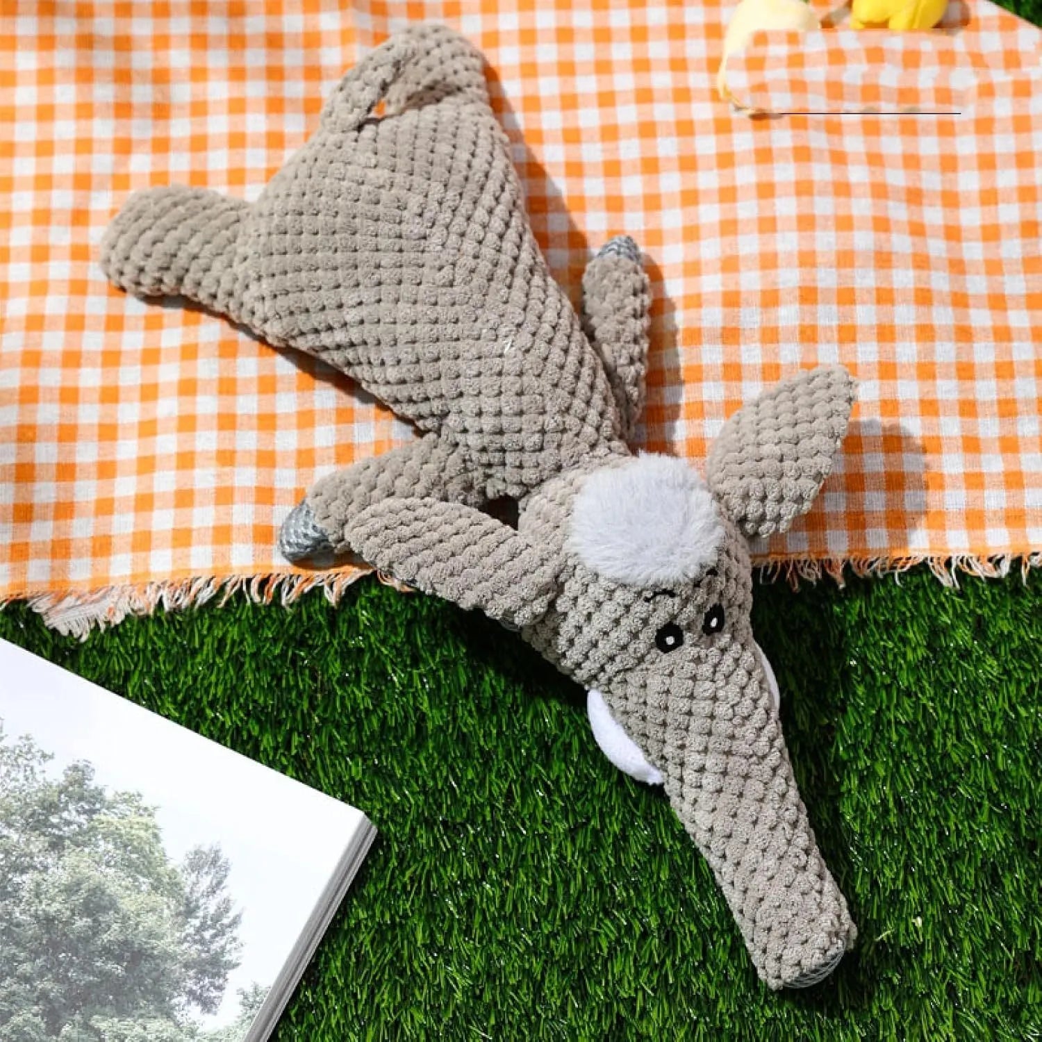 Grey plush dog toy shaped and textured like an ear of corn with visible kernels, lying on a plain surface.