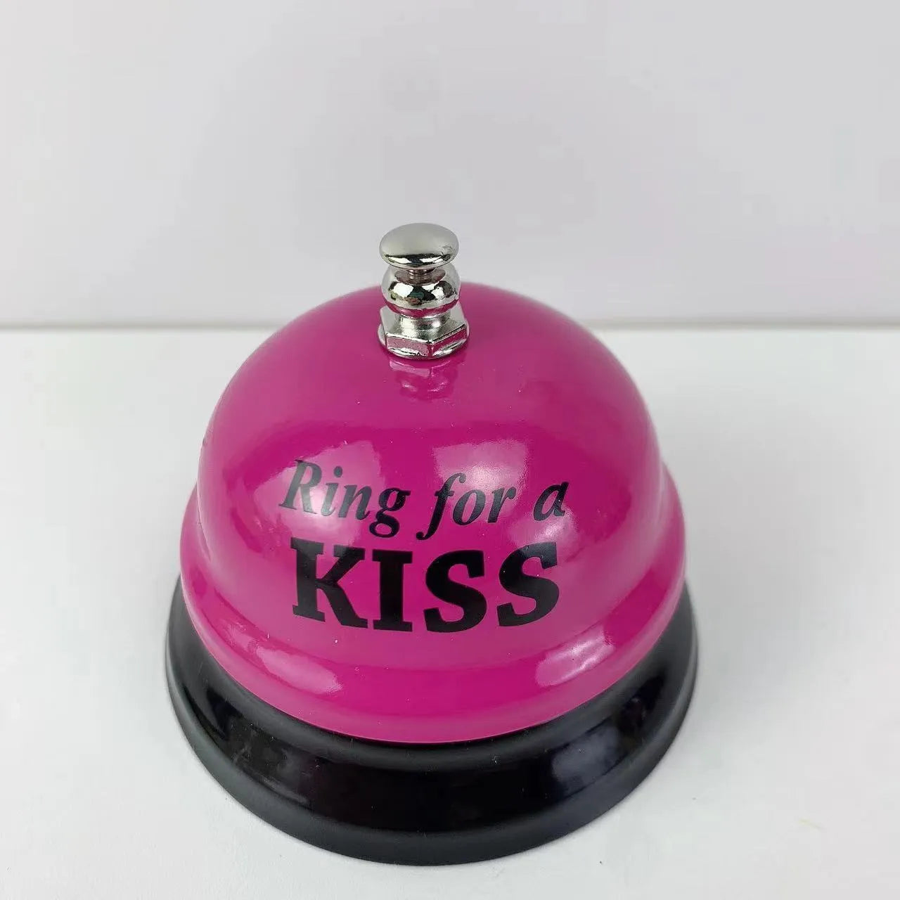 Iron call bell on a desk, shown in one of twelve available colours including red, blue, green, and pink.