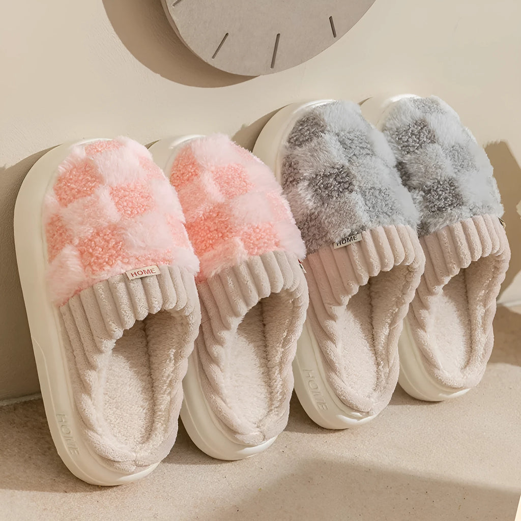 Women's plaid patterned plush slippers with non-slip sole in multiple colours on a wooden floor.