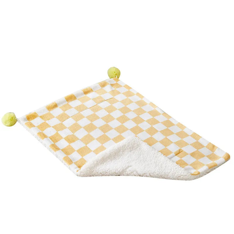 Green plaid patterned soft fleece pet blanket on a sofa, showing fur ball decoration.