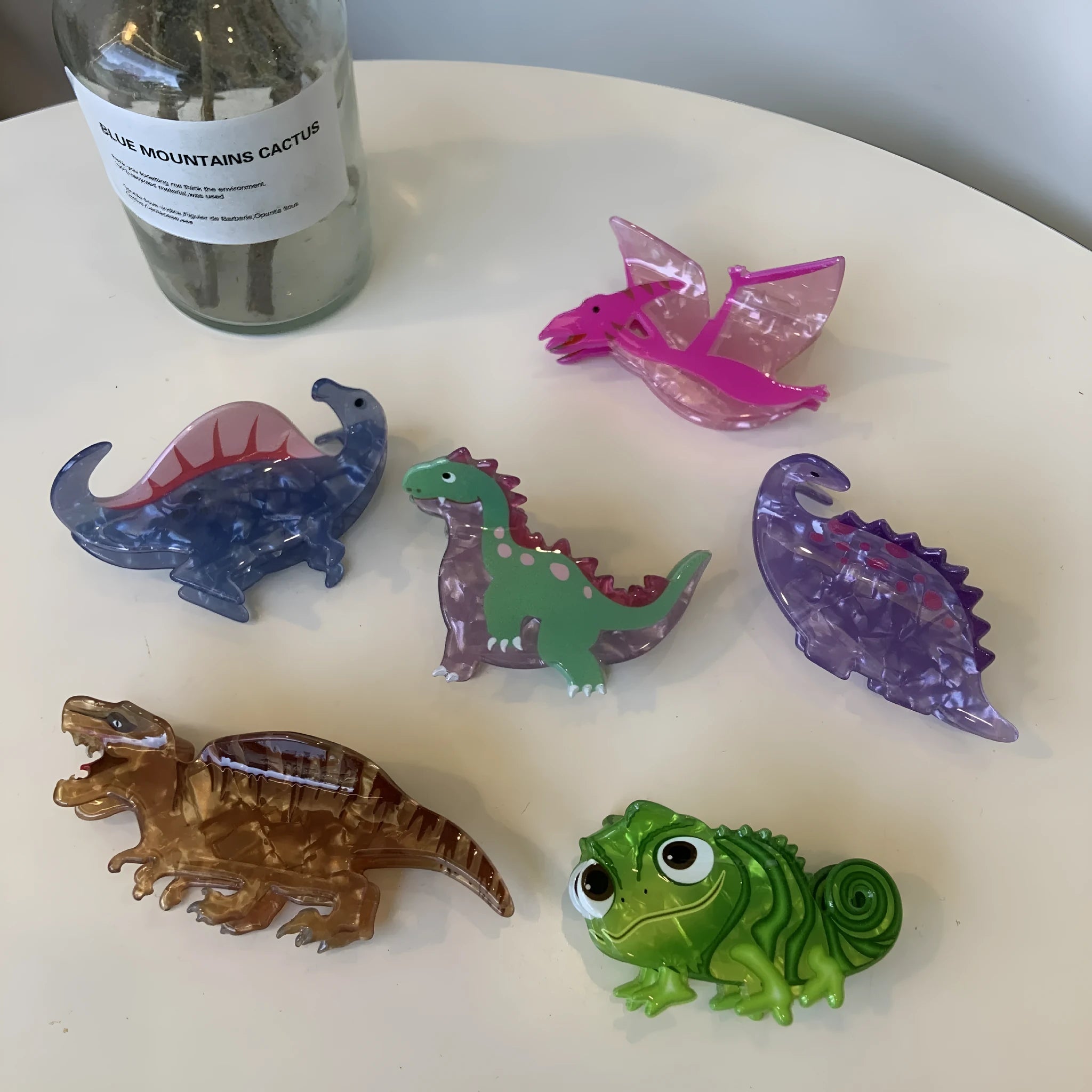 Dinosaur-themed acrylic jaw hair clip showing six colour variations with grip mechanism
