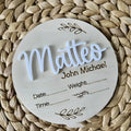 Square wooden baby name sign with birth information, 15 cm wide, in one of three style variants.
