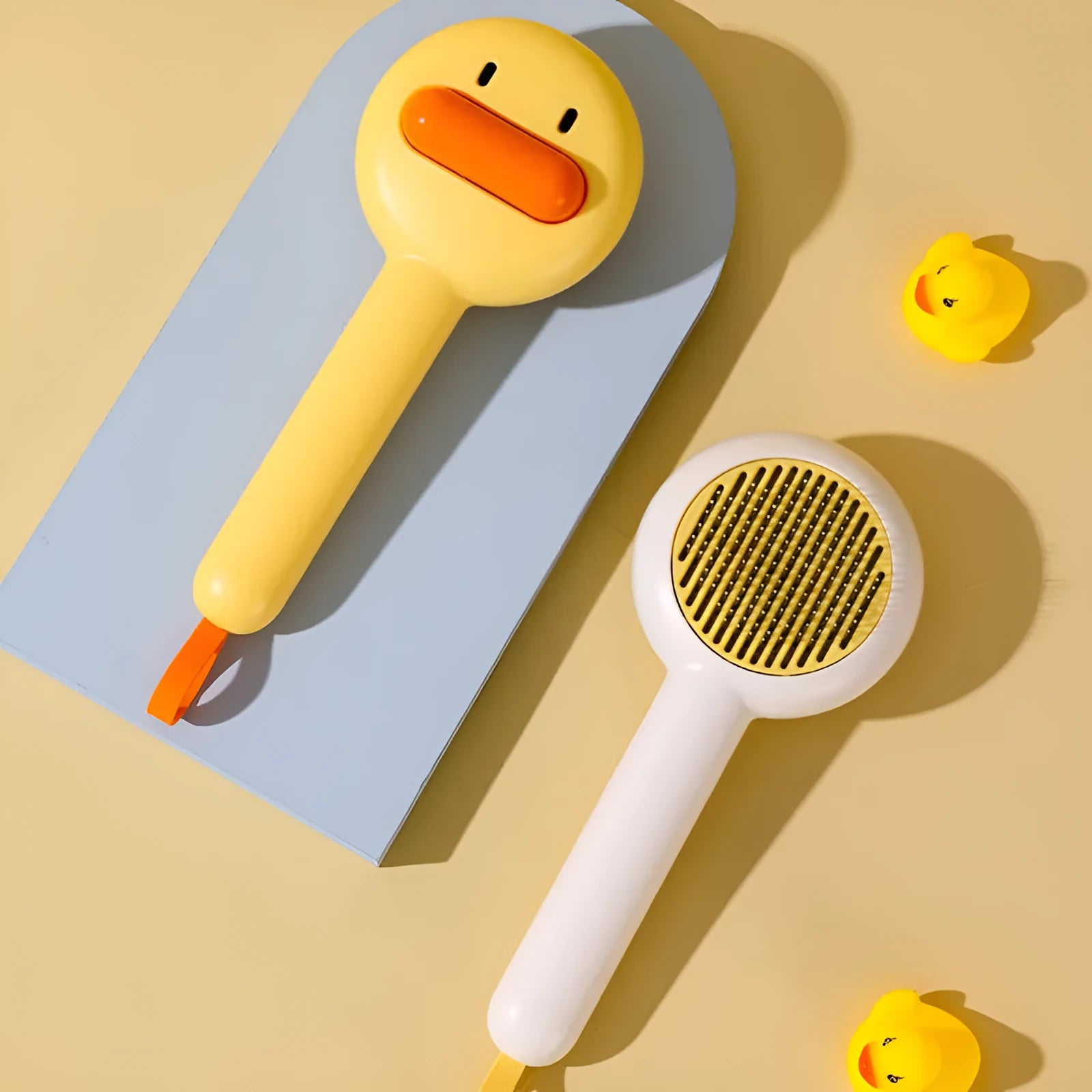 Small yellow duck-shaped pet grooming comb with needle teeth for cat and dog hair removal