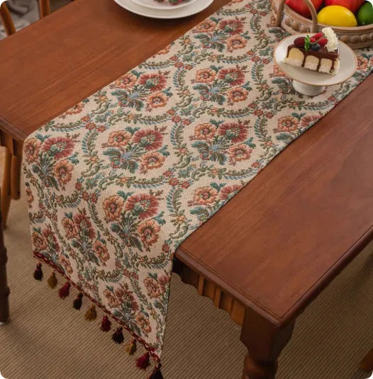 Long decorative table runner with handwoven tassels in a blue ginkgo leaf pattern on a wooden table.