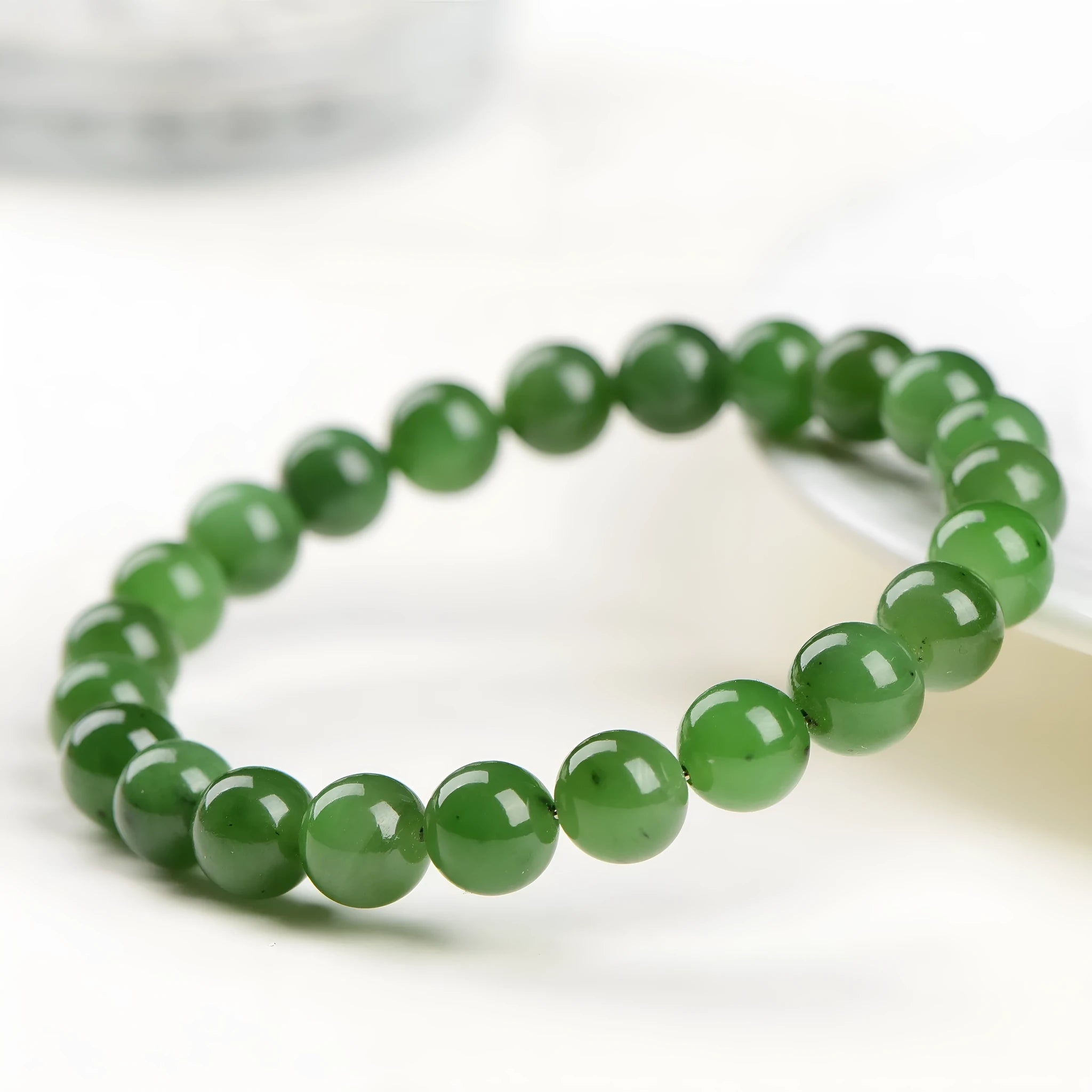 Polished Hetian jade bead bracelet in jasper colours, shown in various bead sizes on a wrist.