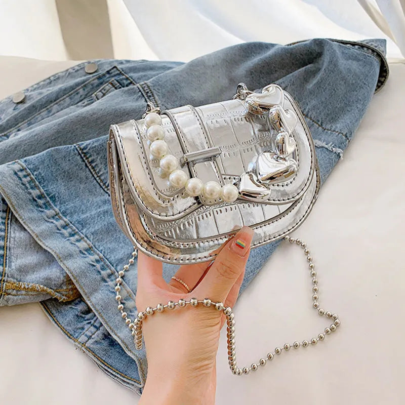 Silver laser pearl tote saddle girl mini crossbody bag with single strap on a mannequin.