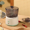 Mini electric meat grinder in light green with transparent cup and stainless steel blades