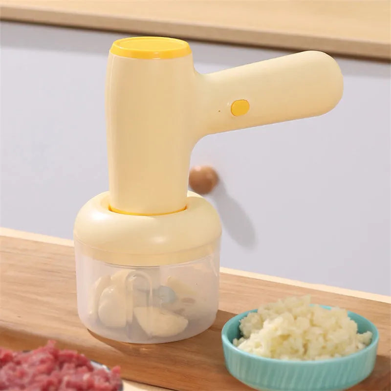 Beige electric garlic chopper with USB charging cable, 250ml cup, and stainless steel blade on kitchen counter