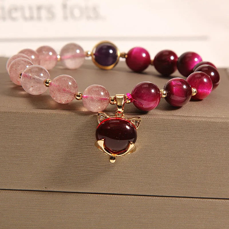 Simple bracelet with a red strawberry crystal on a black elastic rope.