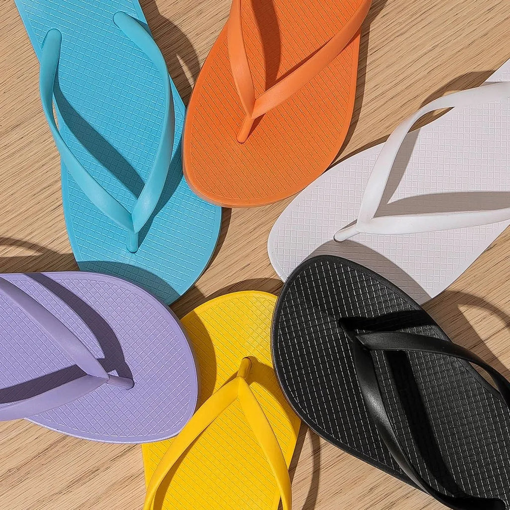 Foldable orange casual slippers with non-slip PVC sole and breathable holes, shown on a beach background.