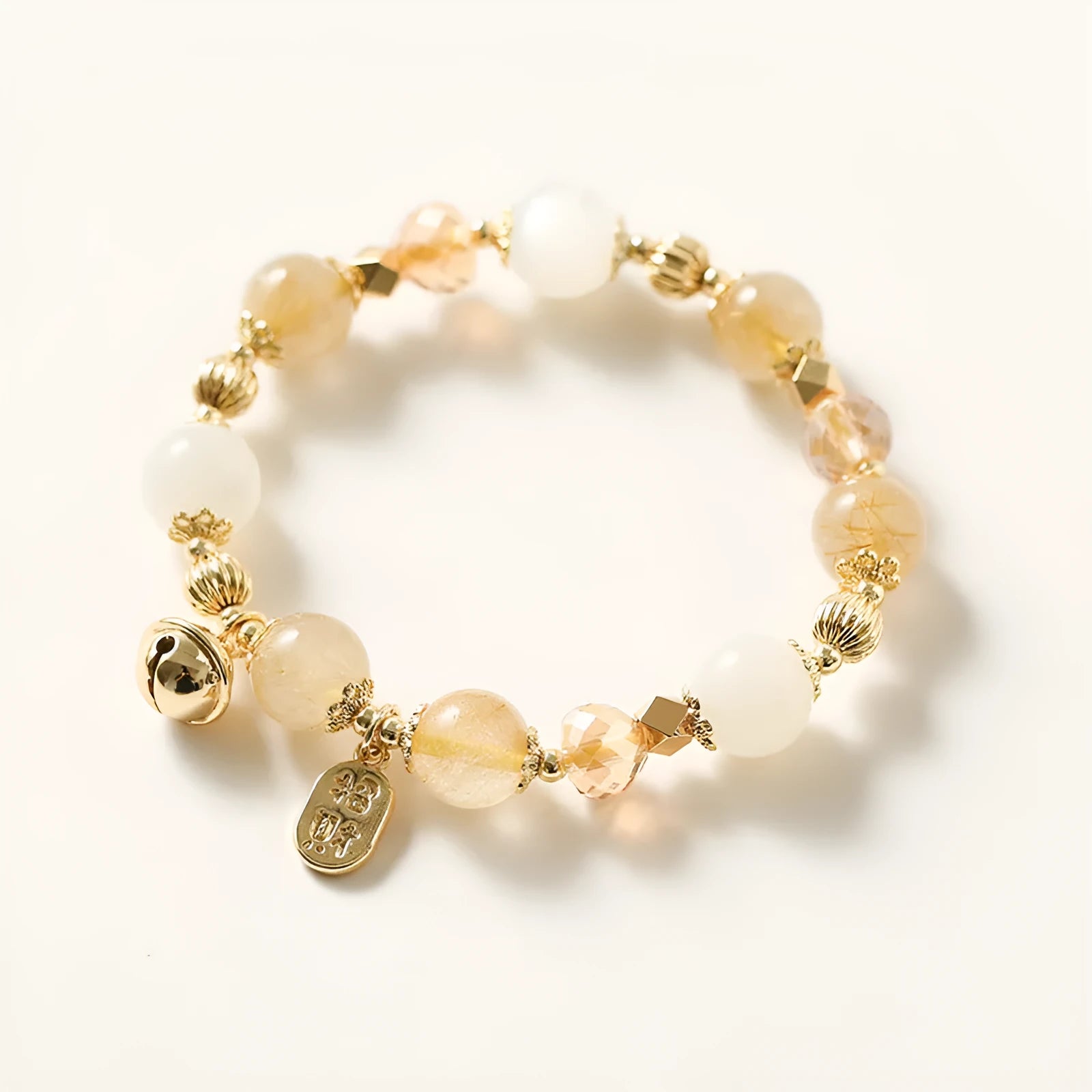 Gold electroplated bracelet with rutilated quartz crystals and a central ringing bell charm