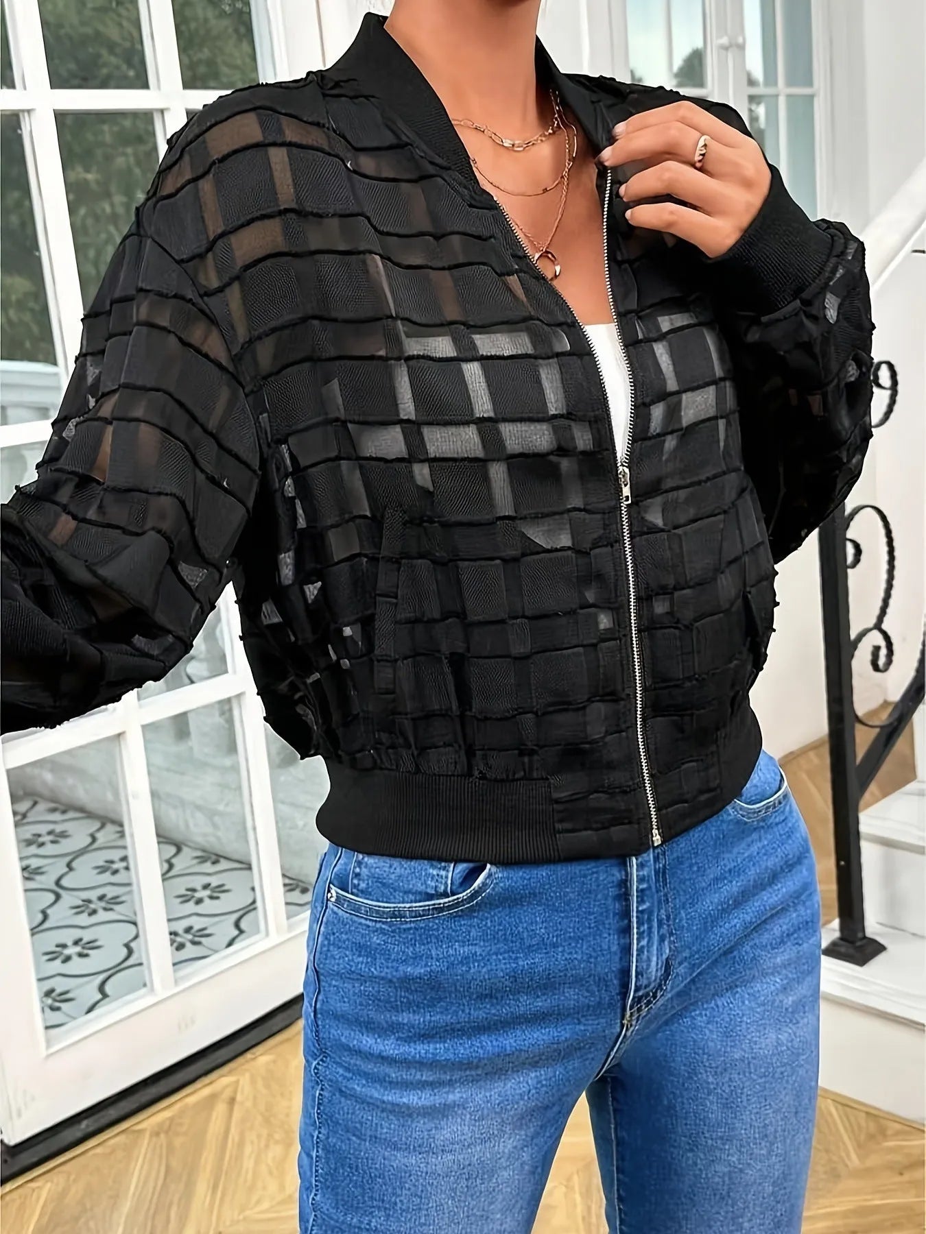 Black women's semi-transparent jacket with geometric pattern and front zipper.