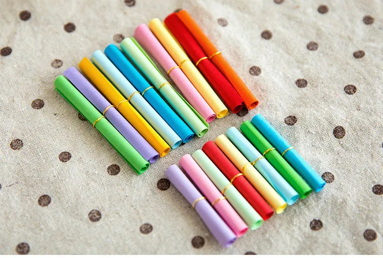 Assorted coloured mini paper scrolls with metal eyelets in sizes 3x7cm, 4x7cm, 5x5cm and 7x7cm.