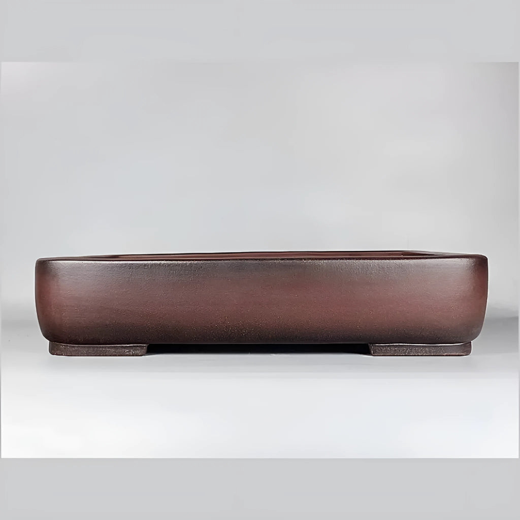 Large handmade antique rectangular purple clay flower pot on a table.