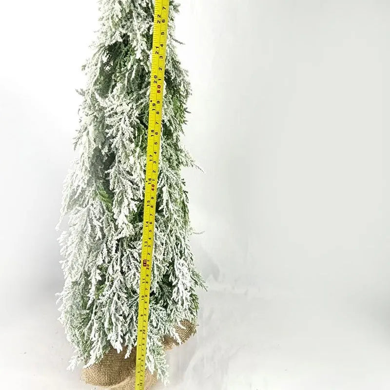 Small 24-inch artificial Christmas tree with snow sprayer finish and integrated lights on desktop