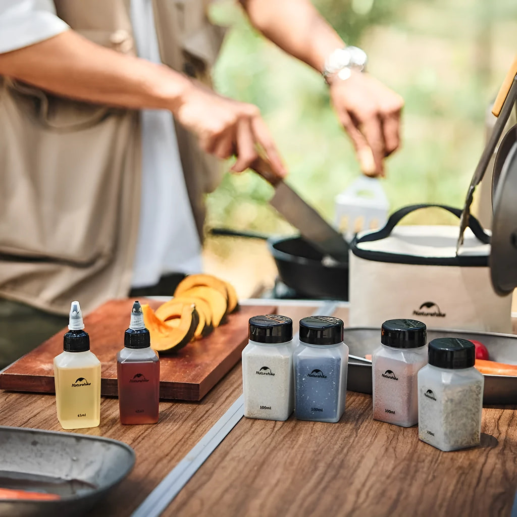 Set of six white portable seasoning bottles with black lids for outdoor picnics and camping.