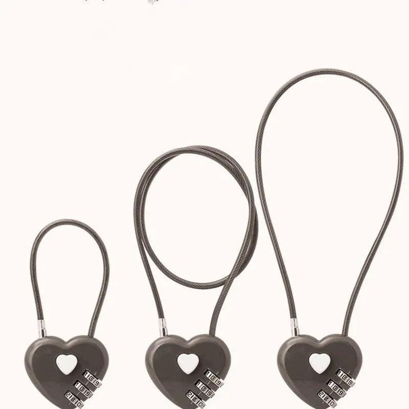 Peach heart shaped combination lock with a black steel rope cable coiled on a table.