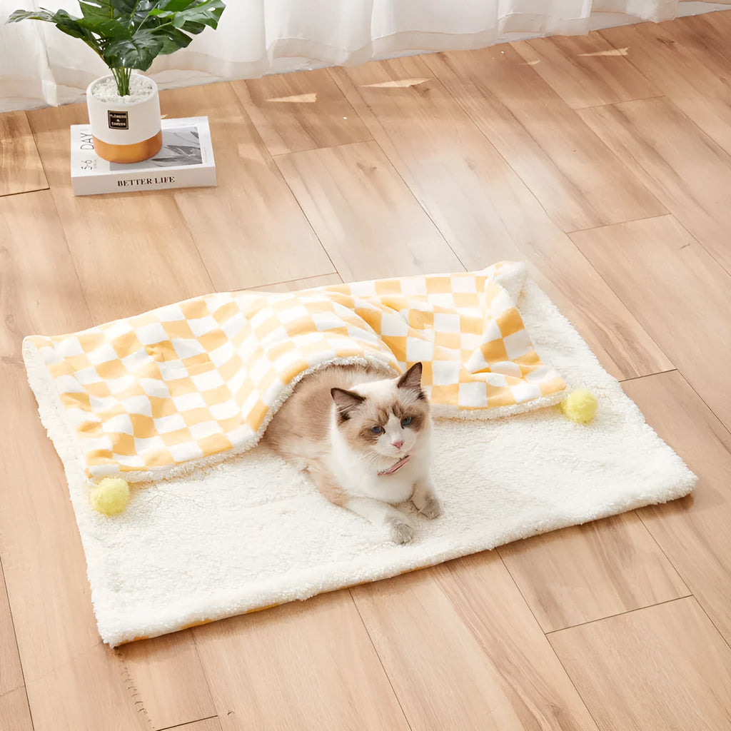 Green plaid patterned soft fleece pet blanket on a sofa, showing fur ball decoration.