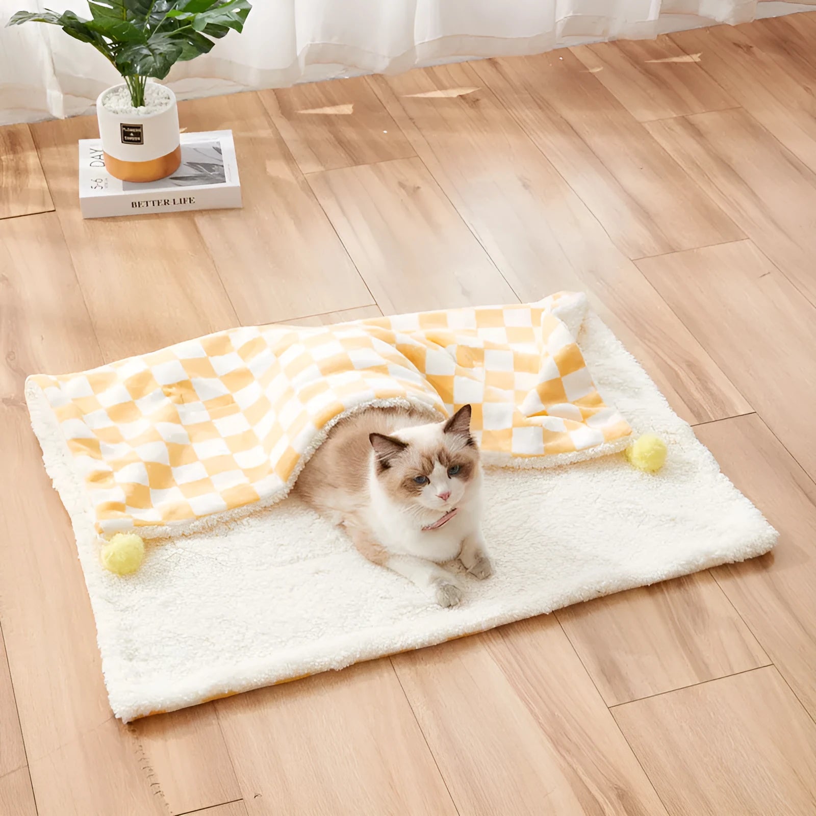 Green plaid patterned soft fleece pet blanket on a sofa, showing fur ball decoration.
