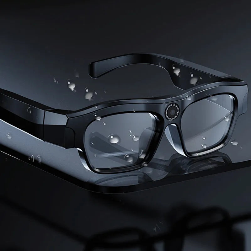 Black head-mounted smart Bluetooth glasses with a built-in camera for video recording on a table with accessories.