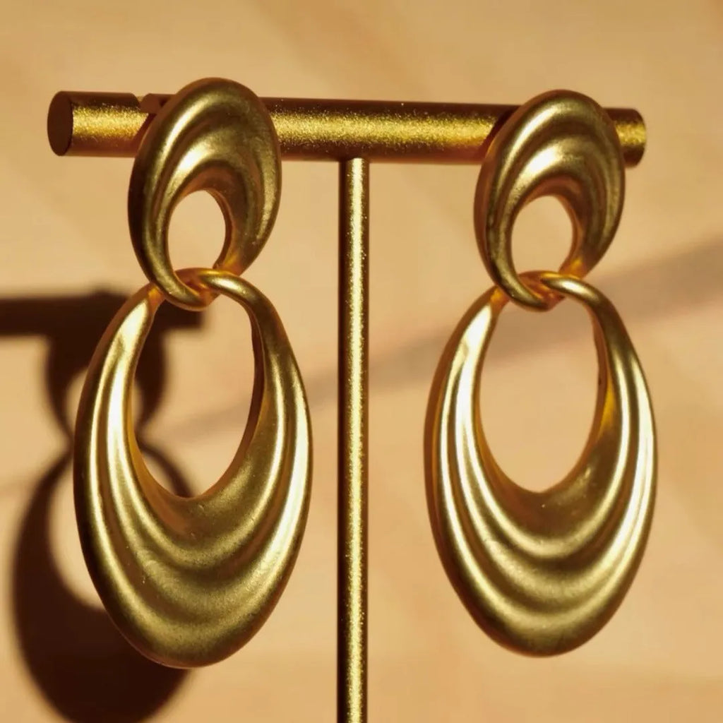 Plain gold coloured U-shaped double circle earrings with a French retro style on a copper background.