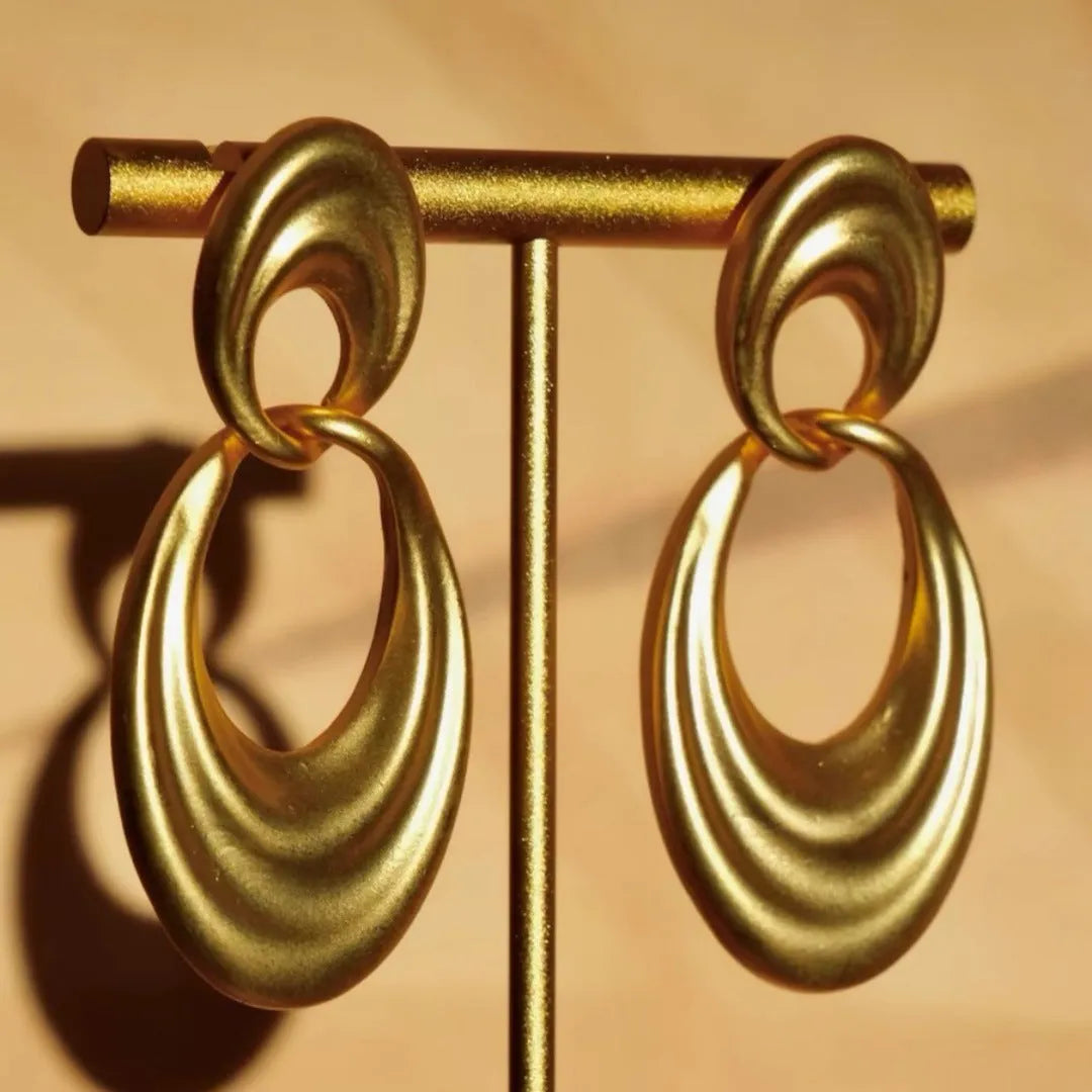 Plain gold coloured U-shaped double circle earrings with a French retro style on a copper background.