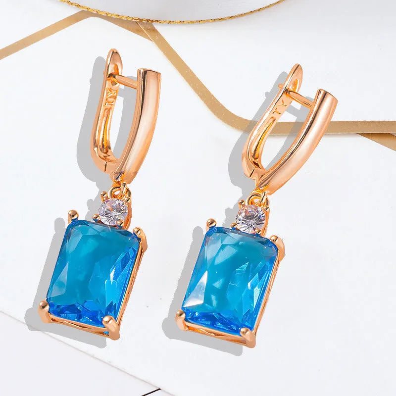 A pair of square-shaped gold and silver electroplated copper earrings on a flat surface.
