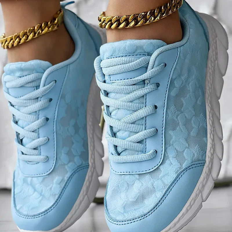 Women's white canvas running shoes with flat heel and round toe, showing sports style and lace-up design