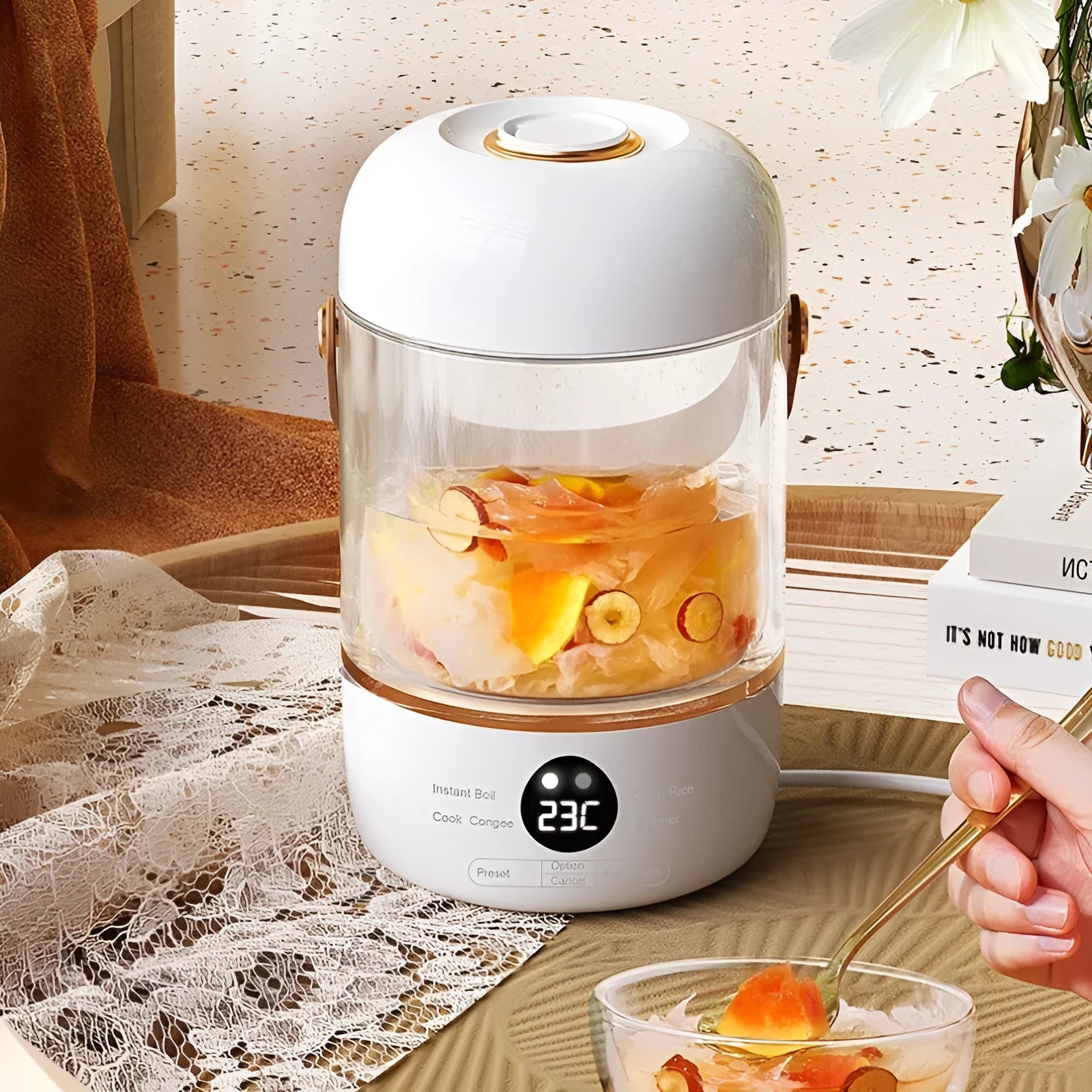 Personal portable electric stew cooker with transparent glass pot and fibreglass body on a counter.