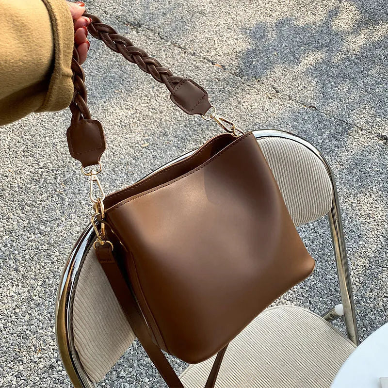 Unisex khaki PU leather crossbody bucket bag with woven texture and one shoulder strap.