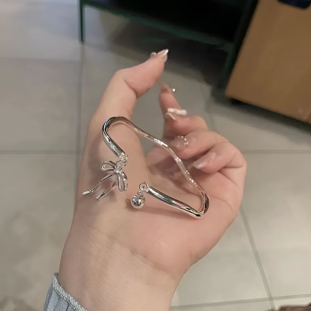 Silver bow adjustable bracelet with zinc alloy construction and electroplated finish.