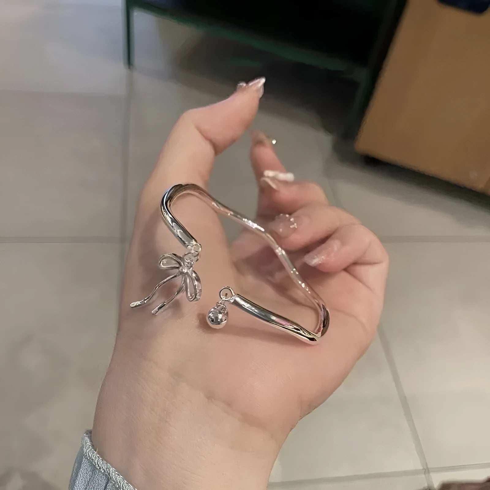 Silver bow adjustable bracelet with zinc alloy construction and electroplated finish.