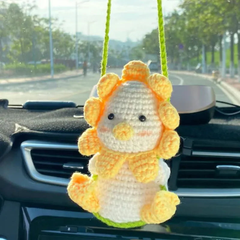 Green and white knitted wool car plant decoration hanging from a rope.