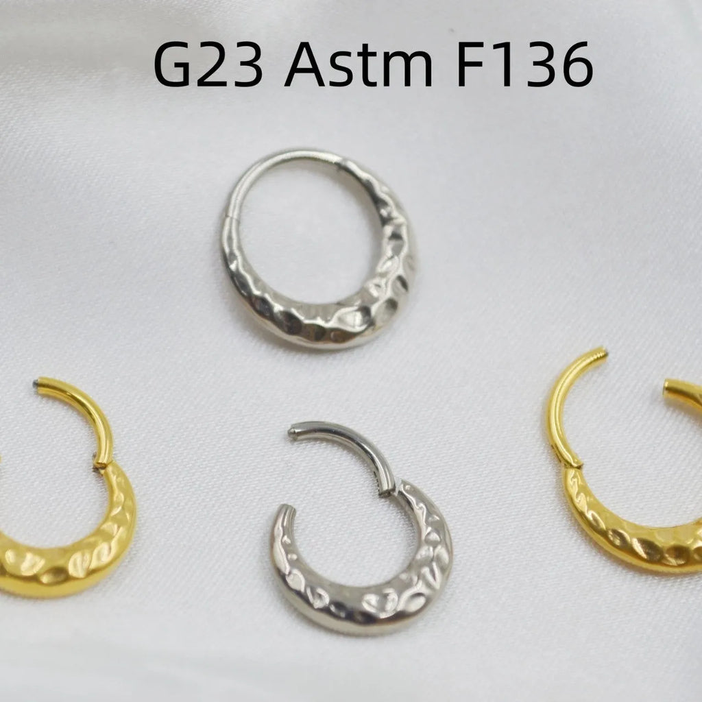 Titanium alloy concave-convex nose ring with carving detail in gold and silver anodised finishes.